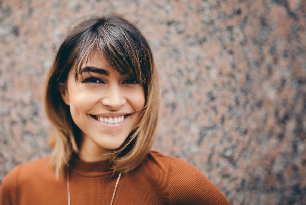 A young woman smiles, illustrating happiness and contentment.