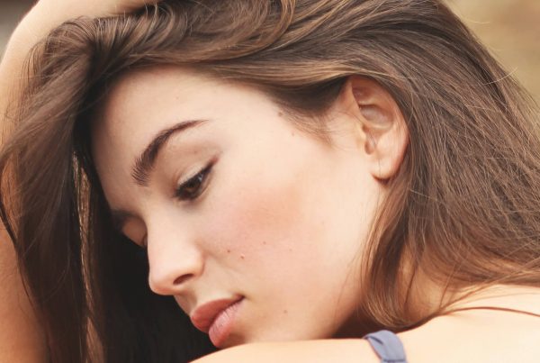 A young woman tilts her head to show excellent skincare.