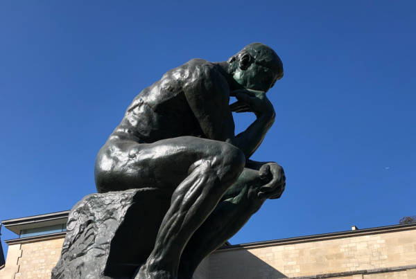 A stone statue of a man sitting down, illustrating contemplation.