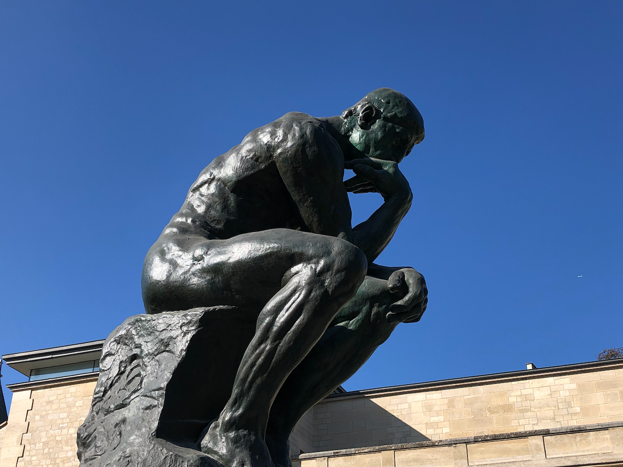A stone statue of a man sitting down, illustrating contemplation.